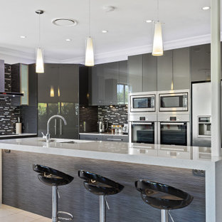 Photo of a large contemporary l-shaped kitchen in Gold Coast - Tweed with an undermount sink, flat-panel cabinets, grey cabinets, grey splashback, matchstick tile splashback, stainless steel appliances, porcelain floors, with island, beige floor and grey benchtop.