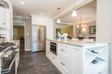 Mid-sized cottage l-shaped ceramic tile and gray floor eat-in kitchen photo in New York with a farmhouse sink, shaker cabinets, yellow cabinets, granite countertops, gray backsplash, glass tile backsplash, stainless steel appliances and an island