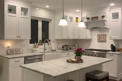 Example of a mid-sized transitional l-shaped dark wood floor and brown floor eat-in kitchen design in Boston with a farmhouse sink, shaker cabinets, white cabinets, quartzite countertops, white backsplash, subway tile backsplash, stainless steel appliances, an island and white countertops