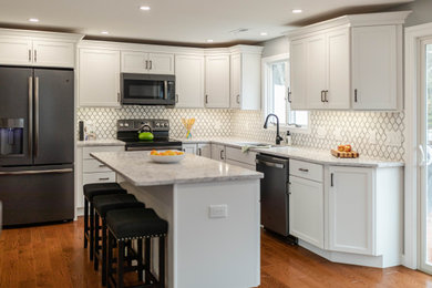 Eat-in kitchen - l-shaped medium tone wood floor eat-in kitchen idea in Manchester with an undermount sink, shaker cabinets, white cabinets, quartzite countertops, white backsplash, mosaic tile backsplash, an island and white countertops