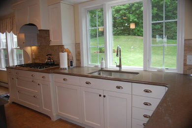 This is an example of a medium sized l-shaped kitchen/diner in Boston with a submerged sink, flat-panel cabinets, white cabinets, granite worktops, beige splashback, ceramic splashback, stainless steel appliances, porcelain flooring and an island.