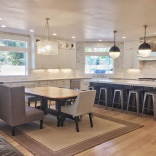 Large transitional l-shaped eat-in kitchen in Phoenix with a farmhouse sink, shaker cabinets, white cabinets, quartz benchtops, white splashback, marble splashback, stainless steel appliances, laminate floors, with island, beige floor and white benchtop.