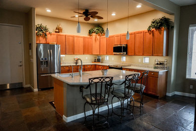 Modern inredning av ett mellanstort vit vitt kök, med en dubbel diskho, luckor med upphöjd panel, skåp i ljust trä, rostfria vitvaror, klinkergolv i porslin, en köksö och brunt golv
