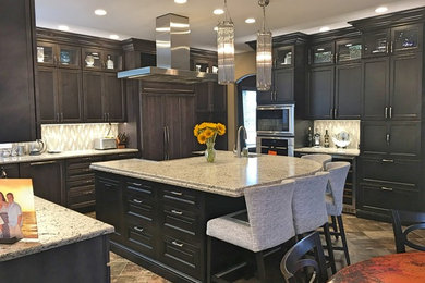 Example of a mid-sized transitional l-shaped brown floor eat-in kitchen design in Denver with an undermount sink, recessed-panel cabinets, dark wood cabinets, granite countertops, gray backsplash, glass tile backsplash, paneled appliances, an island and multicolored countertops