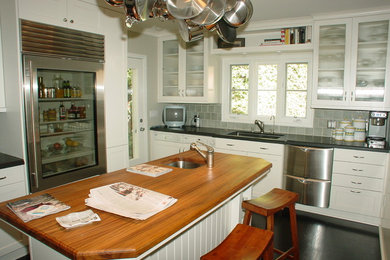 Photo of a medium sized classic l-shaped kitchen/diner in Los Angeles with a submerged sink, recessed-panel cabinets, white cabinets, granite worktops, grey splashback, cement tile splashback, stainless steel appliances, dark hardwood flooring and an island.