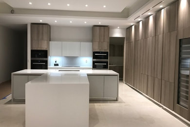 Inspiration for a large modern galley eat-in kitchen remodel in Miami with distressed cabinets, quartz countertops, white backsplash and two islands