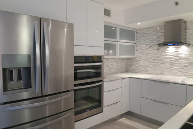 Example of a small minimalist u-shaped bamboo floor enclosed kitchen design in Miami with a single-bowl sink, flat-panel cabinets, white cabinets, marble countertops, white backsplash, ceramic backsplash and stainless steel appliances