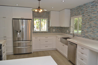 Enclosed kitchen - mid-sized contemporary u-shaped porcelain tile and brown floor enclosed kitchen idea in Miami with a farmhouse sink, recessed-panel cabinets, white cabinets, quartzite countertops, multicolored backsplash, matchstick tile backsplash, stainless steel appliances and a peninsula