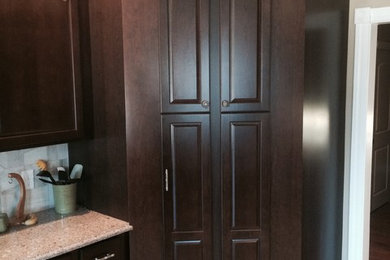 Example of a classic kitchen pantry design in Philadelphia with raised-panel cabinets and medium tone wood cabinets