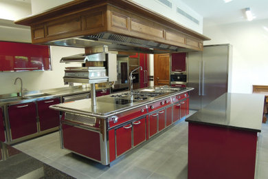 Photo of a large classic kitchen in Other with red cabinets, stainless steel worktops and multiple islands.