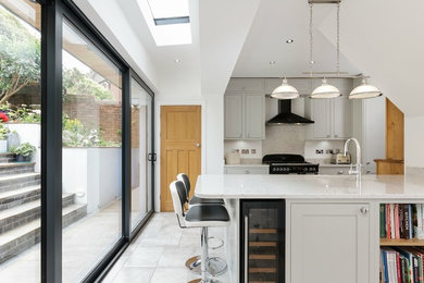 This is an example of a medium sized contemporary single-wall kitchen in Other with a submerged sink, grey cabinets, grey splashback, an island, grey floors, white worktops, shaker cabinets and black appliances.