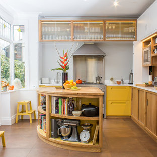 Large retro l-shaped kitchen in Manchester with an integrated sink, flat-panel cabinets, yellow cabinets, engineered stone countertops, stainless steel appliances, porcelain flooring, an island, brown floors and grey splashback.