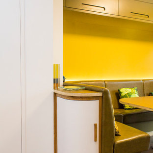 Photo of a large midcentury l-shaped eat-in kitchen in Manchester with an integrated sink, flat-panel cabinets, yellow cabinets, quartz benchtops, stainless steel appliances, porcelain floors, with island and brown floor.