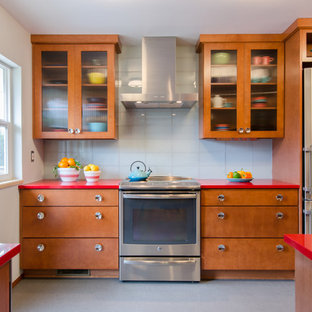 This is an example of a mid-sized midcentury galley separate kitchen in Seattle with a single-bowl sink, flat-panel cabinets, medium wood cabinets, quartz benchtops, glass tile splashback, stainless steel appliances, vinyl floors, no island and white splashback.