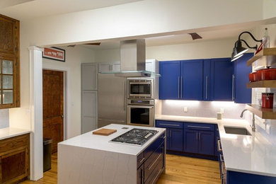 Example of a mid-sized 1950s light wood floor kitchen design in Other with shaker cabinets, blue cabinets, solid surface countertops, blue backsplash, ceramic backsplash, stainless steel appliances and white countertops