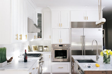 Inspiration for a large transitional l-shaped dark wood floor open concept kitchen remodel in Atlanta with a farmhouse sink, shaker cabinets, white cabinets, marble countertops, white backsplash, ceramic backsplash, stainless steel appliances and an island
