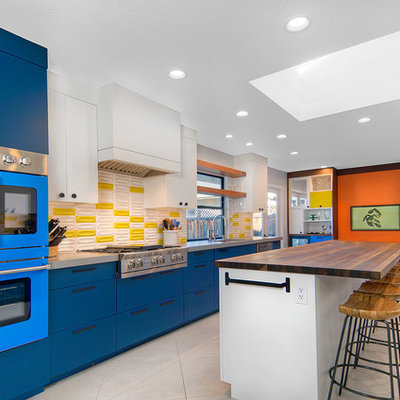 Example of a trendy galley ceramic tile and white floor eat-in kitchen design in San Francisco with an undermount sink, flat-panel cabinets, blue cabinets, quartz countertops, yellow backsplash, ceramic backsplash, colored appliances, an island and gray countertops