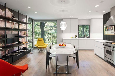 Large retro kitchen/diner in Chicago with an integrated sink, flat-panel cabinets, white cabinets, composite countertops, white splashback, stainless steel appliances, light hardwood flooring and no island.