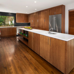Large midcentury kitchen in Seattle with an undermount sink, flat-panel cabinets, quartz benchtops, black splashback, cement tile splashback, stainless steel appliances, medium hardwood floors, with island, medium wood cabinets and brown floor.