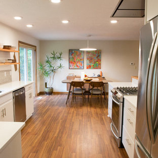 This is an example of a mid-sized midcentury galley open plan kitchen in Other with an undermount sink, flat-panel cabinets, white cabinets, quartzite benchtops, grey splashback, porcelain splashback, stainless steel appliances, vinyl floors and a peninsula.