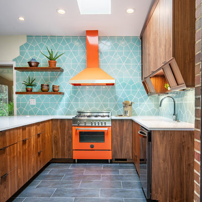 Example of a mid-sized 1960s u-shaped ceramic tile and black floor kitchen design in Cincinnati with a single-bowl sink, flat-panel cabinets, quartz countertops, ceramic backsplash, colored appliances, an island, gray countertops, dark wood cabinets and blue backsplash
