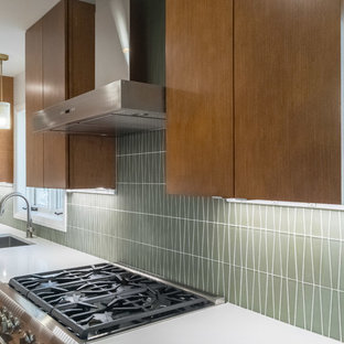 Design ideas for a large midcentury l-shaped open plan kitchen in Raleigh with an undermount sink, flat-panel cabinets, medium wood cabinets, quartz benchtops, green splashback, glass tile splashback, stainless steel appliances, medium hardwood floors and with island.