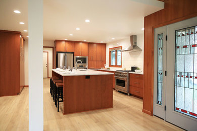 Example of a large mid-century modern l-shaped vinyl floor and beige floor open concept kitchen design in Other with an undermount sink, flat-panel cabinets, medium tone wood cabinets, quartz countertops, white backsplash, ceramic backsplash, stainless steel appliances, an island and white countertops