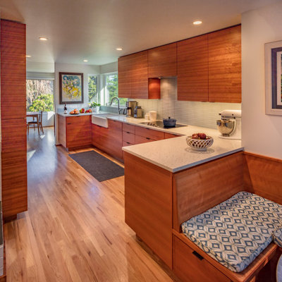 Inspiration for a mid-sized 1960s u-shaped medium tone wood floor kitchen pantry remodel in Seattle with a farmhouse sink, flat-panel cabinets, medium tone wood cabinets, quartz countertops, white backsplash, ceramic backsplash, paneled appliances and white countertops