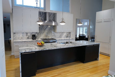 Mittelgroße Moderne Wohnküche mit flächenbündigen Schrankfronten, weißen Schränken, Küchengeräten aus Edelstahl, hellem Holzboden und Kücheninsel in Raleigh