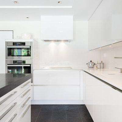 Mid-sized trendy l-shaped black floor and slate floor kitchen photo in Ottawa with flat-panel cabinets, white cabinets, quartzite countertops, white backsplash, stainless steel appliances and an island
