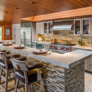 Photo of a mid-sized transitional galley open plan kitchen in Austin with grey cabinets, granite benchtops, stainless steel appliances, light hardwood floors, with island, recessed-panel cabinets, multi-coloured splashback and slate splashback.