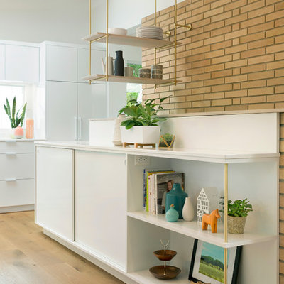 Mid-sized 1950s medium tone wood floor kitchen photo in Minneapolis with an undermount sink, flat-panel cabinets, white cabinets, quartz countertops, glass sheet backsplash, stainless steel appliances and an island