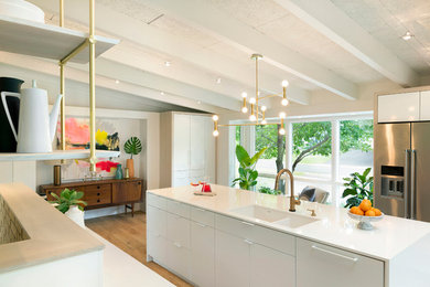Inspiration for a mid-sized mid-century modern medium tone wood floor kitchen remodel in Minneapolis with an undermount sink, flat-panel cabinets, white cabinets, quartz countertops, glass sheet backsplash, stainless steel appliances and an island