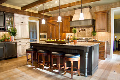 Large farmhouse u-shaped light wood floor and beige floor enclosed kitchen photo in Other with an undermount sink, raised-panel cabinets, dark wood cabinets, granite countertops, beige backsplash, travertine backsplash, paneled appliances, an island and beige countertops