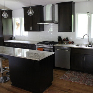 Photo of a large midcentury eat-in kitchen in Minneapolis with an undermount sink, flat-panel cabinets, dark wood cabinets, granite benchtops, white splashback, subway tile splashback, stainless steel appliances, light hardwood floors and with island.