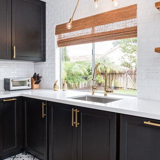 Mid-sized midcentury u-shaped separate kitchen in Los Angeles with an undermount sink, shaker cabinets, black cabinets, quartz benchtops, white splashback, subway tile splashback, porcelain floors, no island and white floor.