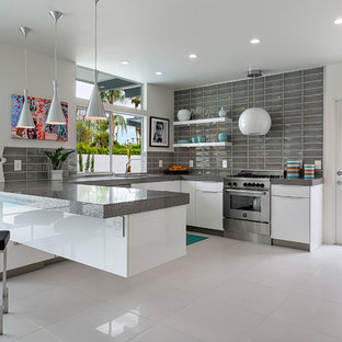 Immagine di una cucina ad U minimalista con ante lisce, ante bianche, paraspruzzi grigio, elettrodomestici in acciaio inossidabile e penisola