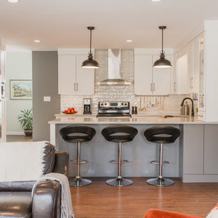 This is an example of a small midcentury u-shaped open plan kitchen in Other with an undermount sink, shaker cabinets, white cabinets, quartz benchtops, white splashback, subway tile splashback, stainless steel appliances, vinyl floors, a peninsula, brown floor and white benchtop.