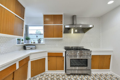 Photo of a midcentury kitchen in Dallas with flat-panel cabinets, medium wood cabinets, white splashback, ceramic splashback, stainless steel appliances, no island and white worktops.