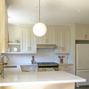 Design ideas for a small midcentury u-shaped separate kitchen in Toronto with an undermount sink, shaker cabinets, beige cabinets, quartz benchtops, white splashback, ceramic splashback, stainless steel appliances, vinyl floors, a peninsula, brown floor and grey benchtop.