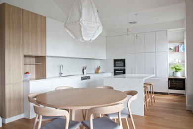 Свежая идея для дизайна: кухня-гостиная среднего размера в современном стиле с двойной мойкой, белыми фасадами, столешницей из кварцита, фартуком из кварцевого агломерата, светлым паркетным полом и островом - отличное фото интерьера