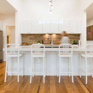 This is an example of a contemporary l-shaped kitchen in Melbourne with a double-bowl sink, open cabinets, white cabinets, quartz benchtops, stone tile splashback, stainless steel appliances, medium hardwood floors, white benchtop, blue splashback, with island and brown floor.