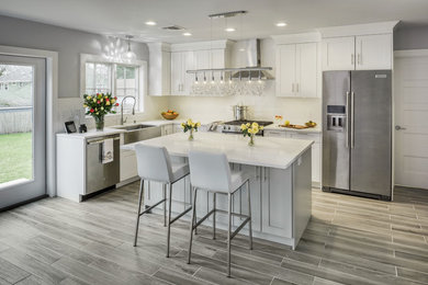 Large transitional l-shaped porcelain tile and gray floor open concept kitchen photo in Providence with a farmhouse sink, shaker cabinets, gray cabinets, quartzite countertops, subway tile backsplash, stainless steel appliances, an island and white countertops