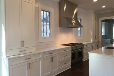 Inspiration for a large transitional single-wall dark wood floor kitchen remodel in Atlanta with an undermount sink, shaker cabinets, white cabinets, white backsplash, subway tile backsplash, stainless steel appliances and an island