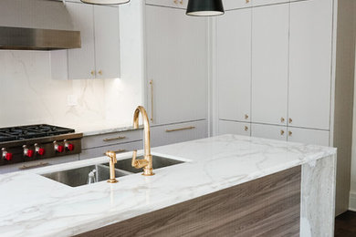 Example of a large minimalist l-shaped medium tone wood floor and brown floor eat-in kitchen design with an undermount sink, flat-panel cabinets, gray cabinets, marble countertops, white backsplash, stone slab backsplash, stainless steel appliances, an island and white countertops