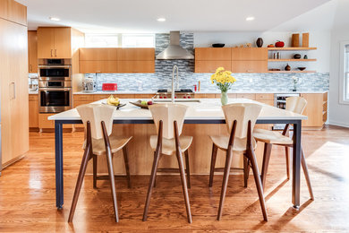 Foto på ett mellanstort funkis vit kök, med en undermonterad diskho, släta luckor, skåp i ljust trä, bänkskiva i kvarts, grått stänkskydd, stänkskydd i glaskakel, rostfria vitvaror, mellanmörkt trägolv, en köksö och brunt golv