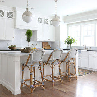 Maritime Küche in L-Form mit Landhausspüle, Schrankfronten im Shaker-Stil, weißen Schränken, Küchenrückwand in Weiß, Rückwand aus Metrofliesen, braunem Holzboden und Kücheninsel in Salt Lake City