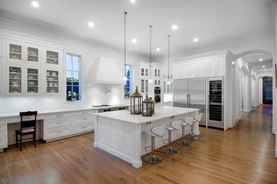 Eat-in kitchen - mid-sized transitional single-wall dark wood floor eat-in kitchen idea in New York with an undermount sink, recessed-panel cabinets, white cabinets, marble countertops, white backsplash, subway tile backsplash, stainless steel appliances and an island