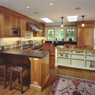 Mid-sized traditional eat-in kitchen ideas - Inspiration for a mid-sized timeless u-shaped medium tone wood floor eat-in kitchen remodel in New York with paneled appliances, wood countertops, a farmhouse sink, shaker cabinets, medium tone wood cabinets, white backsplash, porcelain backsplash and an island