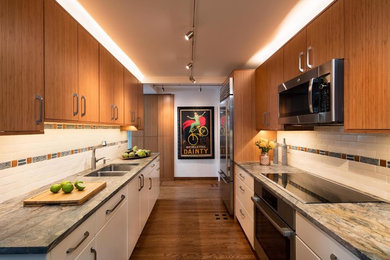 Inspiration for a mid-sized transitional galley medium tone wood floor enclosed kitchen remodel in Chicago with a double-bowl sink, flat-panel cabinets, white cabinets, granite countertops, white backsplash, ceramic backsplash, stainless steel appliances and no island